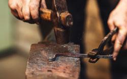 Blacksmith makes an artistic forging of hot metal on the anvil